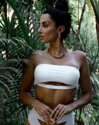 Flavia Medina, modelo argentina, posando con un atrevido top blanco y joyas doradas en un entorno selvático