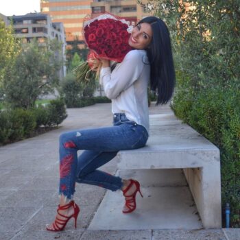 Flavia Medina, hermosa modelo argentina, sosteniendo un gran ramo de rosas rojas mientras posa con una sonrisa cautivadora