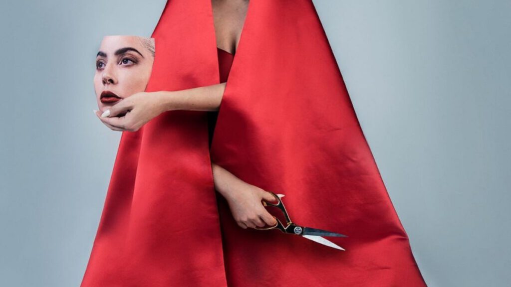 Lady Gaga con vestido rojo sosteniendo su rostro en su mano