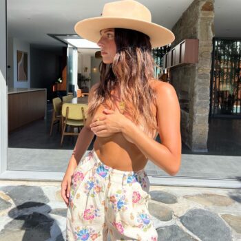 Modelo australiana Steph Mandich posando con un sombrero de ala ancha y un conjunto floral en un entorno moderno