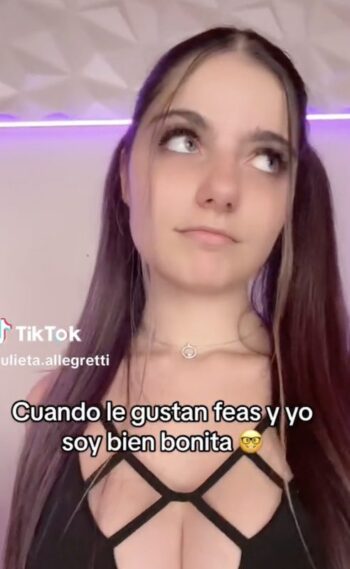 Julieta Girl mirando a la cámara con una expresión sugerente, usando un atuendo negro con transparencias y detalles en látex que resalta sus curvas