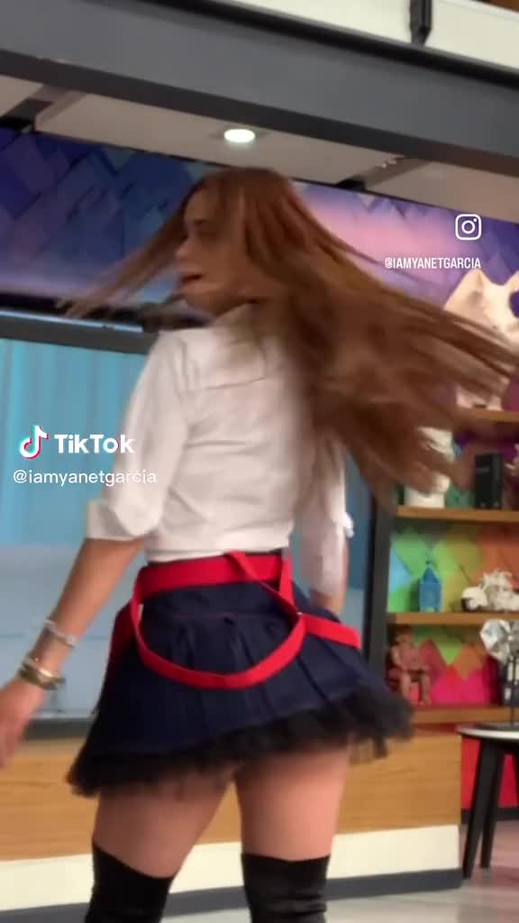 Yanet Garcia con mini falda, camisa blanca y medias estilo colegiala