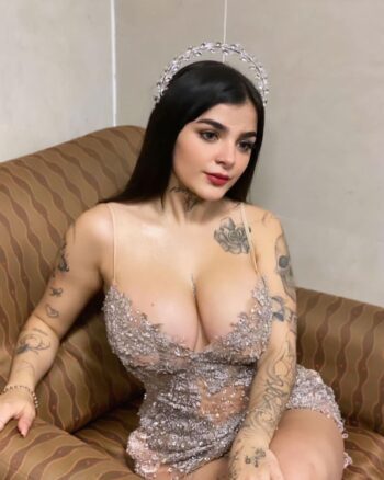 Videos Karely Ruiz posando con vestido plateado con aplicaciones brillantes que acentúa su busto y silueta