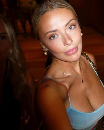 Corinna Kopf, una influencer digital y modelo, posando en un elegante conjunto de lencería azul con accesorios dorados