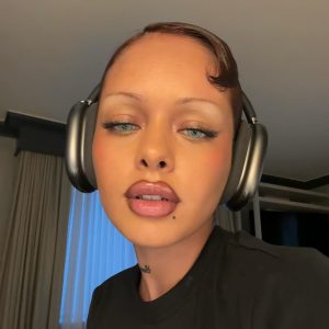 Imagen de Khleopatre Donezo, atractiva modelo francesa con maquillaje y peinado impecable, usando auriculares y posando con actitud seductora