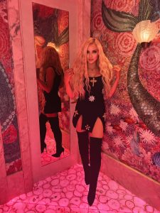 DJMelReeves posa en un vestido negro con botas modernas.