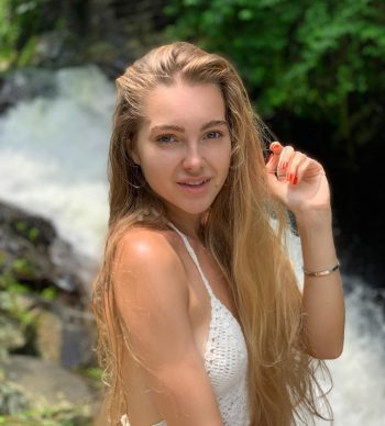 Cerise Spice posando con una mano en el cabello, luciendo un top blanco y minifalda negra ajustada