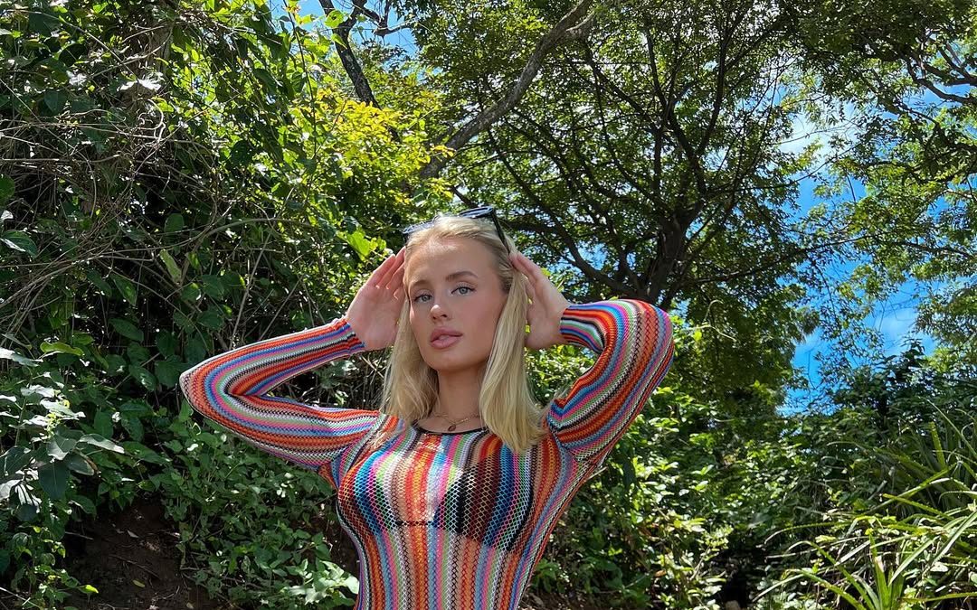 Vega Thompson en vestido arcoíris de estilo retro en un jardín frondoso