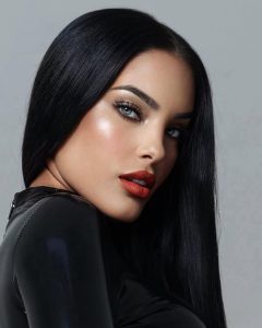 Yeimmy Rodríguez con cabello oscuro, labios rojos y mirada intensa en un fondo gris