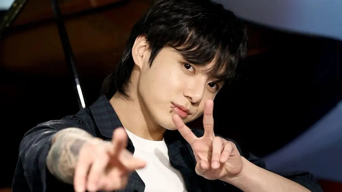 Jungkook de BTS haciendo el símbolo de paz con sus manos y mirada seria
