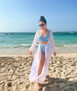 Kelly Bustamante posa con confianza en la playa, luciendo bikini azul y elegante kimono blanco de lunares