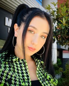 Kelly Bustamante posa con un vestido floral verde y negro, mirando a la cámara con confianza