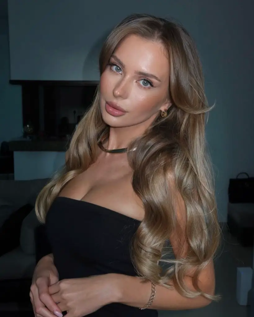 Alexandra Shulgovich posando con confianza en un vestido negro ajustado que resalta sus curvas