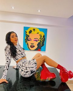 Belén Negri posa con vestido floral ajustado y botas altas de charol rojo, destacando sus curvas y piernas tonificadas