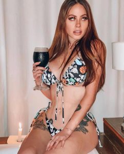 Ignacia Michelson posando con un bikini negro y blanco con estampado de calaveras, sosteniendo una bebida oscura
