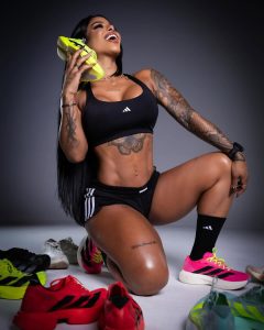 Karishna Ayala sonríe en postura de rodillas, destacando su abdomen tonificado y tatuajes en brazos