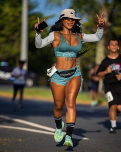 Karishna Ayala sonríe mientras levanta los brazos mostrando su figura atlética con top y gorra deportiva