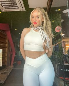 Natalia Rivera posa de frente con un conjunto blanco de top y pantalón ajustados, y una elegante bufanda que enmarca su rostro