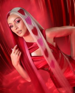 Natalia Rivera posa con cabello largo y ondulado en un vestido rojo ajustado que resalta su figura