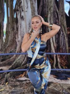 Natalia Rivera posando en un mono azul y dorado con estampado de ondas, resaltando su figura y actitud glamorosa