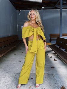 Natalia Rivera luce un conjunto amarillo con top con volantes y pantalón ancho, acentuando su figura con pose confiada