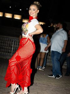 Natalia Rivera sonríe con confianza mientras posa con un vestido rojo de corte ajustado y diseño de malla que resalta su figura