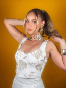 Natalia Rivera posando con elegante vestido de escote pronunciado y accesorios dorados que resaltan su figura