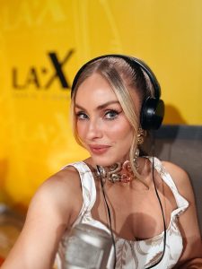 Natalia Rivera con auriculares negros, accesorios de joyería y maquillaje destacando su mirada y expresión serena