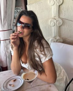 Priscilla Huggins Ortiz con lentes de sol, disfrutando de una bebida en un ambiente lujoso y acogedor