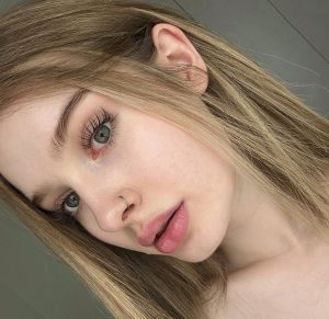 Creadora rusa Comatozze con pestañas voluminosas, ojos verdes y labios rosa nude en pose lateral