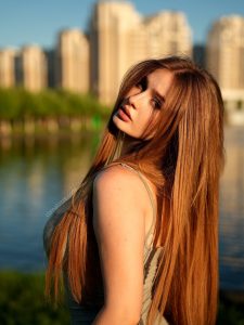 Comatozze modelo rusa cabello castaño largo top beige río arquitectura urbana