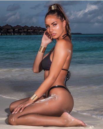 Modelo holandesa Lindsey Van Der Hoeven con bikini negro y accesorios dorados en playa tropical