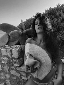 Laura Torrisi actriz italiana con sombrero tejido y pose elegante en jardín de cactus, fotografía editorial en blanco y negro